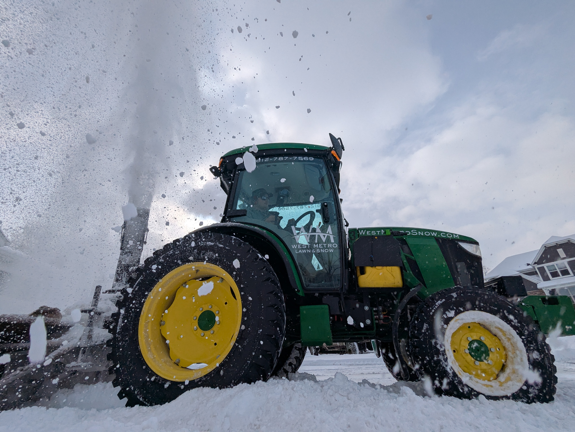 West Metro Lawn & Snow tractor blasting snow during a storm