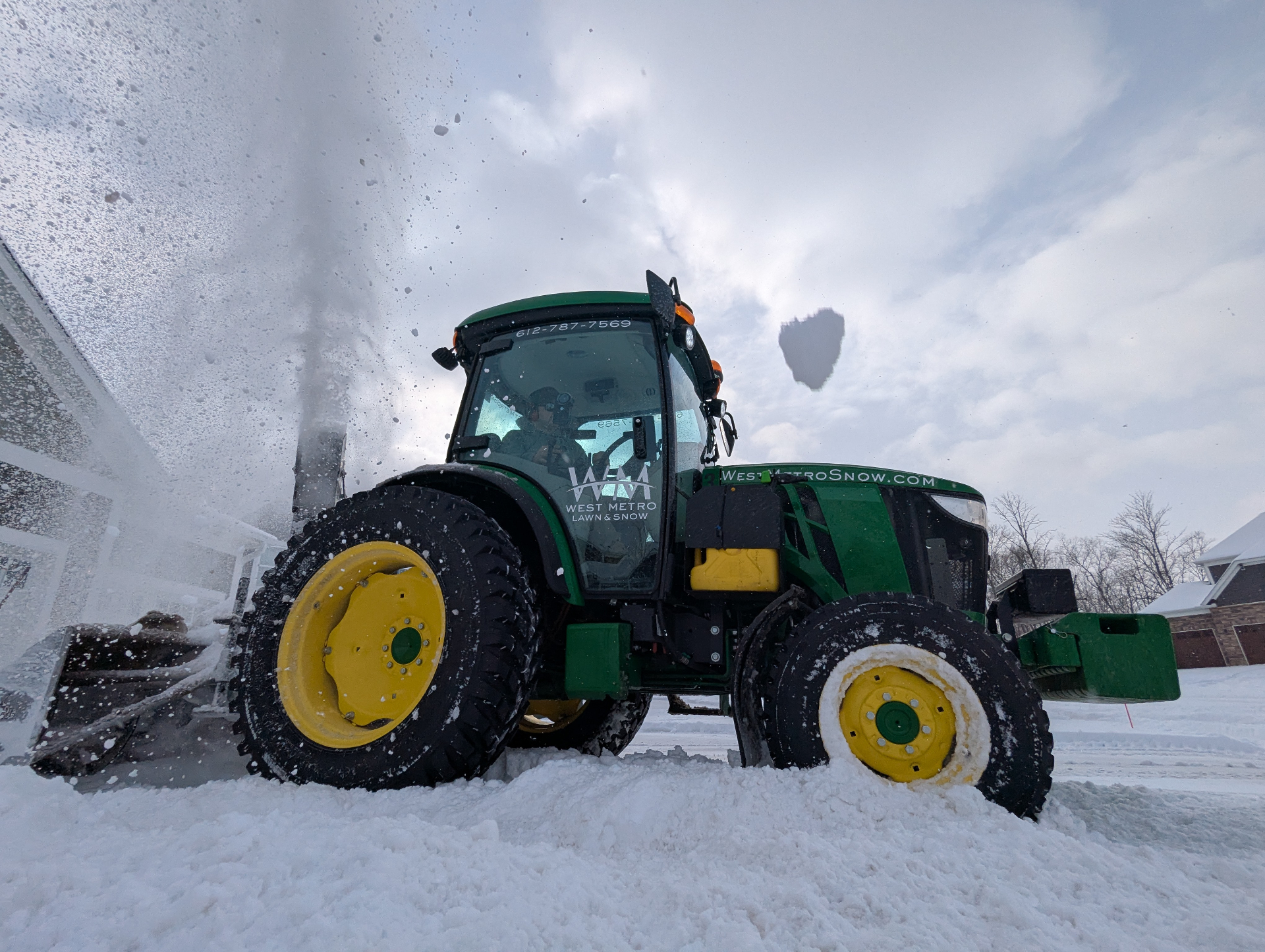 Front view of West Metro snow tractor throwing snow during a winter storm