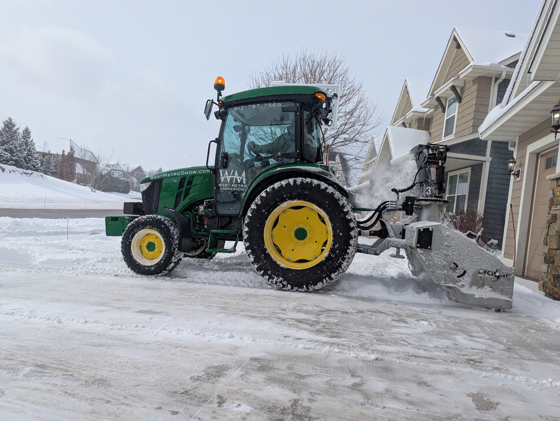 Side view of West Metro snow tractor clearing snow in a neighborhood